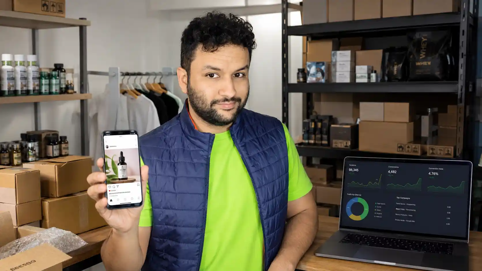 Francisco mostrando anúncio ilustrativo no celular junto a produtos e notebook