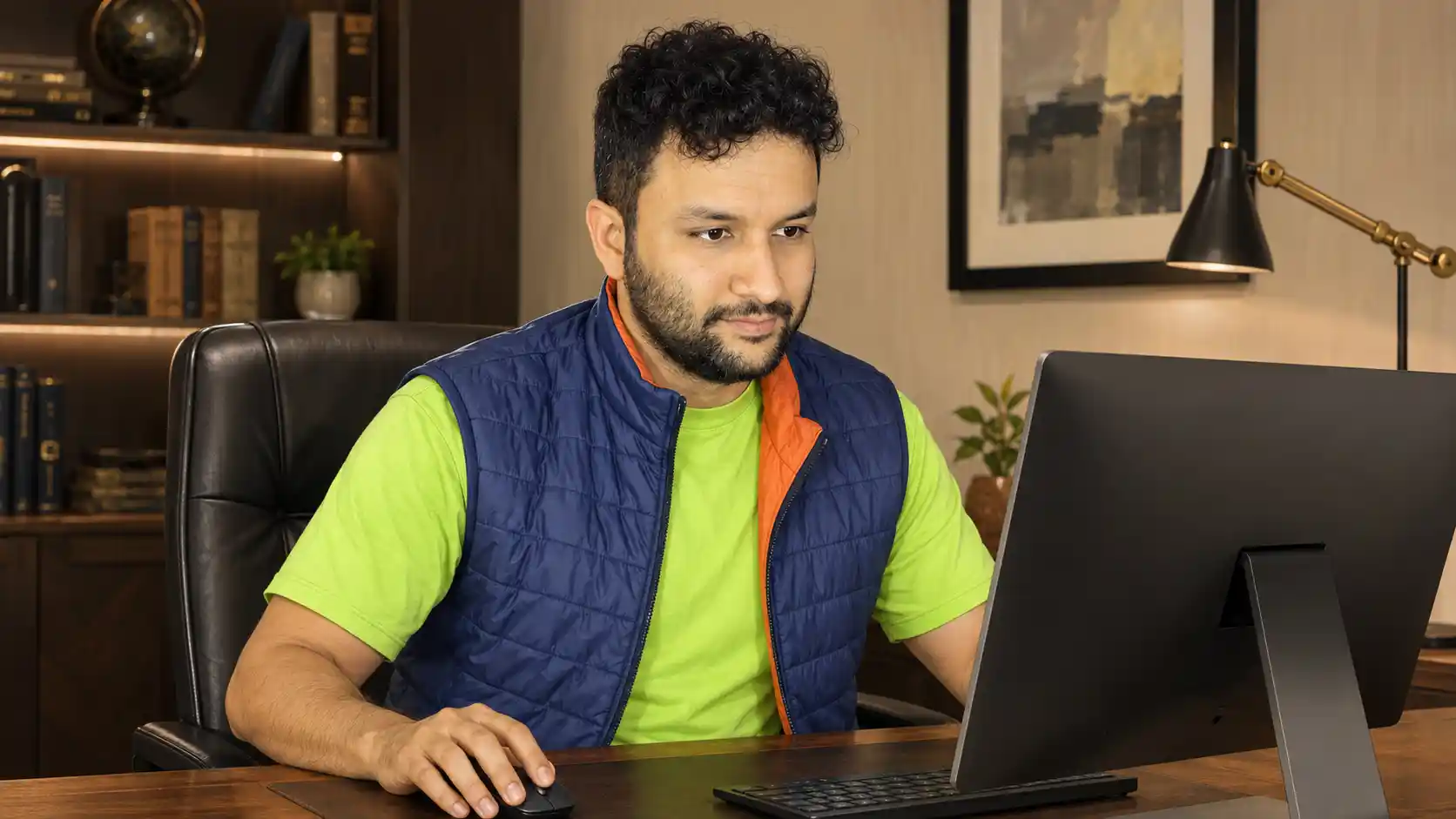 Francisco usando computador em uma mesa de escritório com livros ao fundo