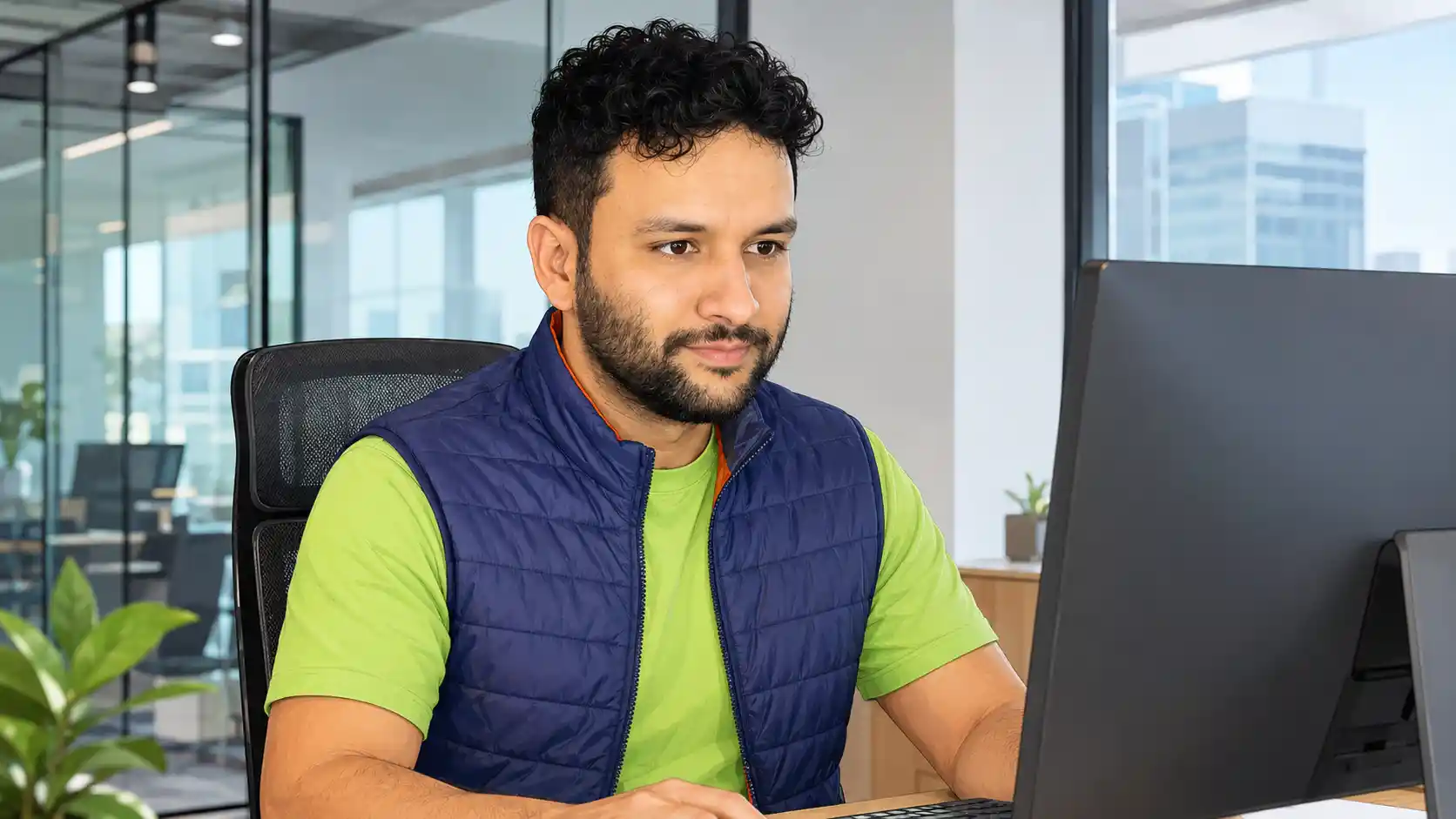 Francisco diante de um monitor em escritório com iluminação natural