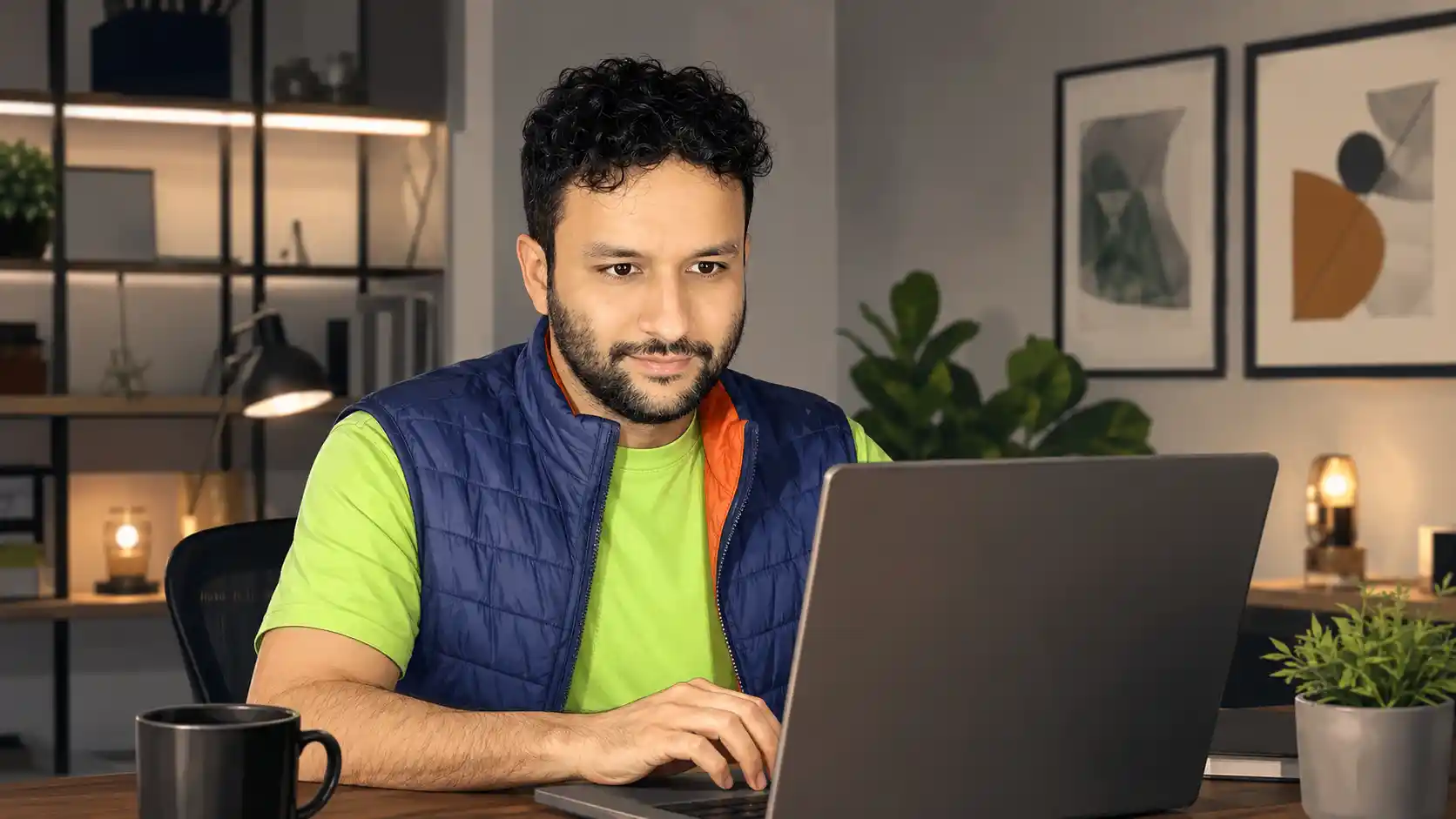 Francisco trabalhando em notebook com livros e luminárias ao fundo